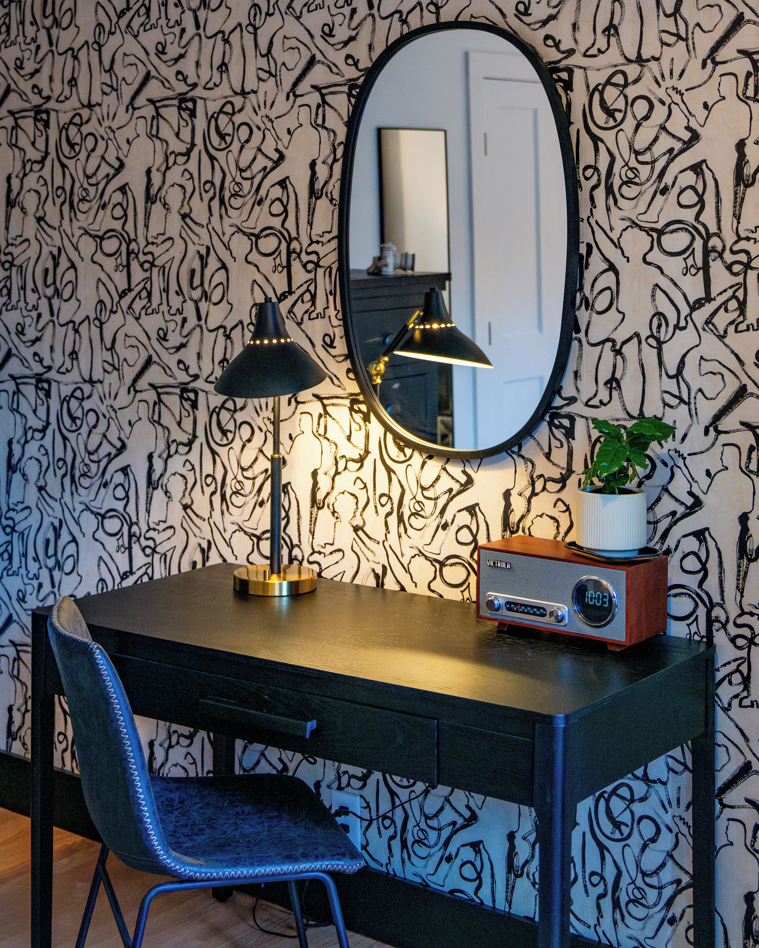 A desk with a chair, a mirror, a lamp, and a radio.