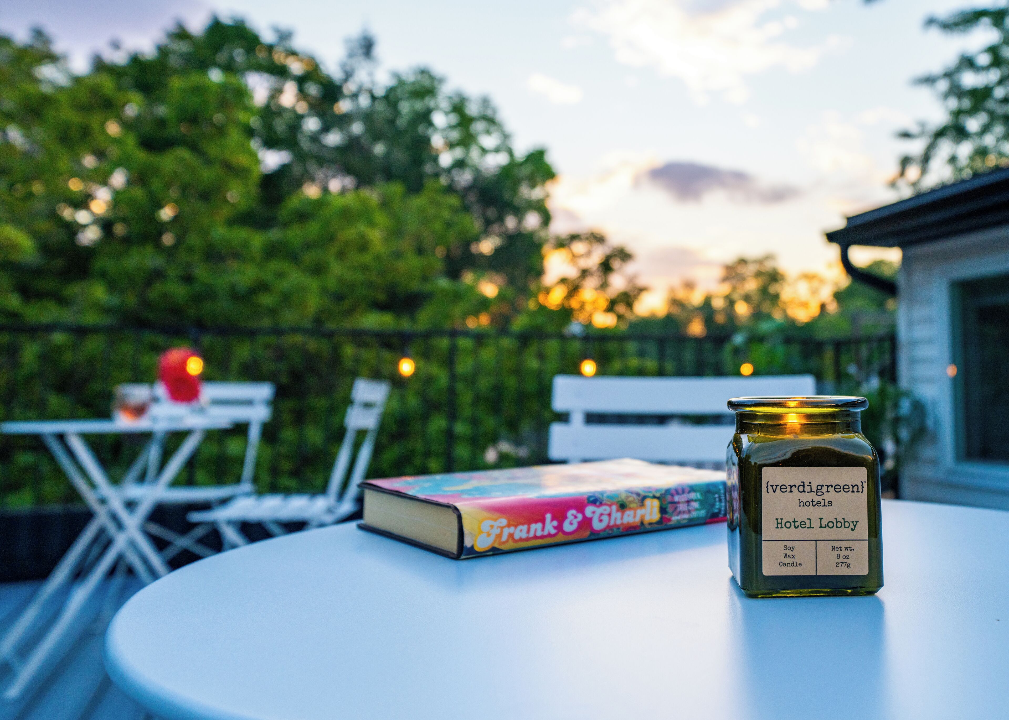 A book titled 'Frank & Charli' and a jar labeled 'verdigreen hotels' on a table outdoors.
