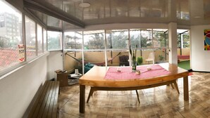 A room with a wooden table, a red and white checkered tablecloth, and a view through large windows. - Hostal Casa Lantana Usaquén - Hostel (Bogotá)