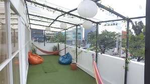 A balcony with artificial grass, a hammock, bean bags, hanging paper lanterns, and potted plants. - Hostal Casa Lantana Usaquén - Hostel (Bogotá)