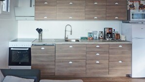 Una cuina compacta amb armaris de fusta, un rentaplat de superfície inox i un microones.