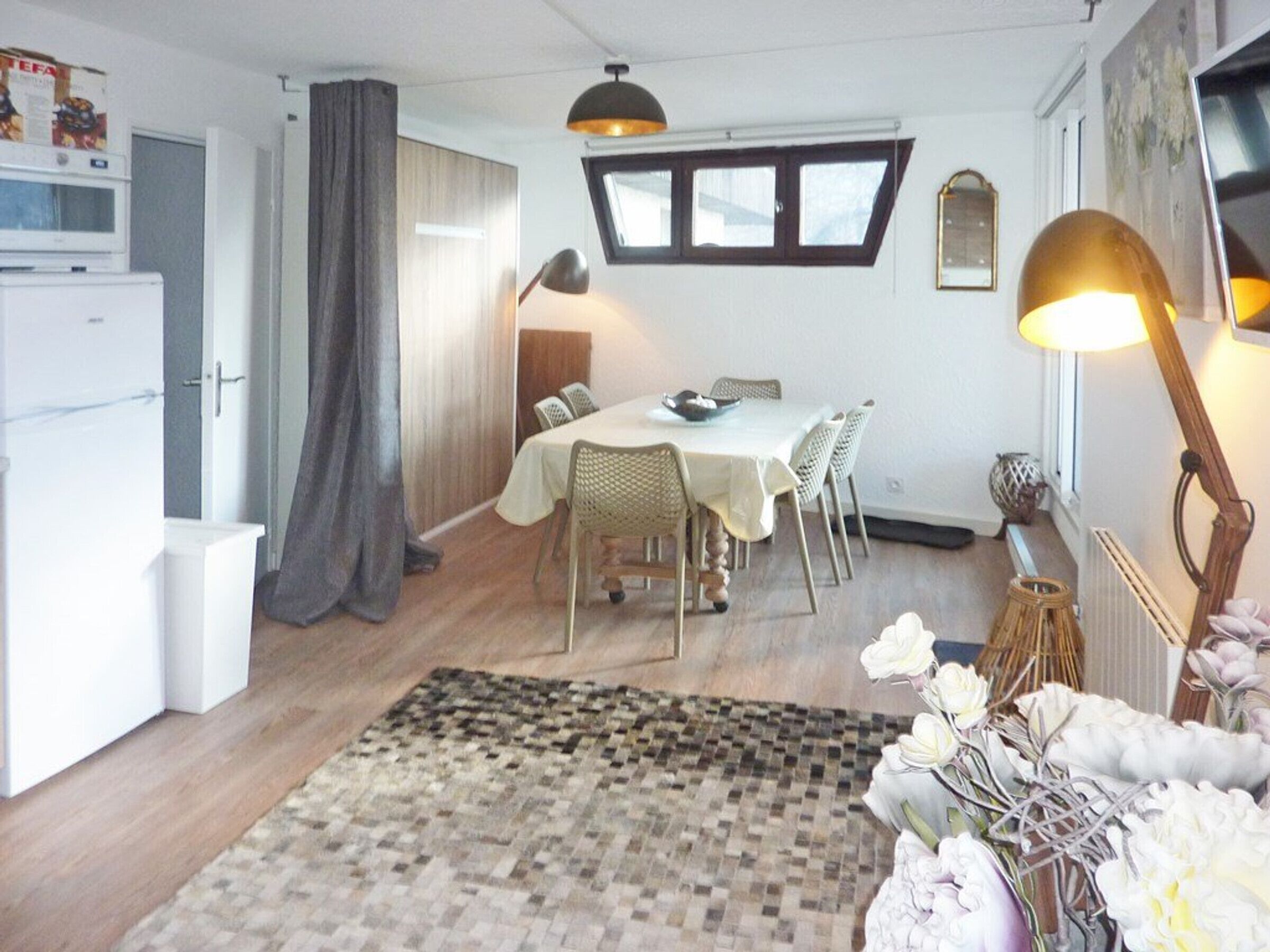 Un espace de vie compact comprenant un coin repas, une cuisine et un petit salon.