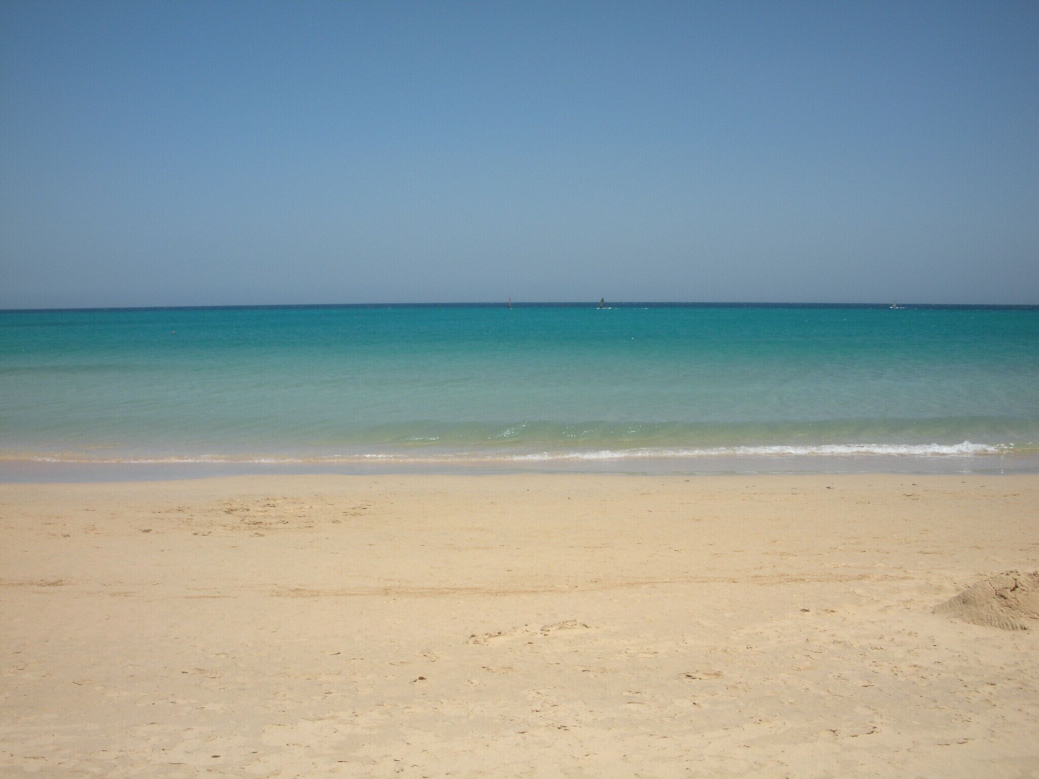 A beach with clear turquoise water and a sandy shore.