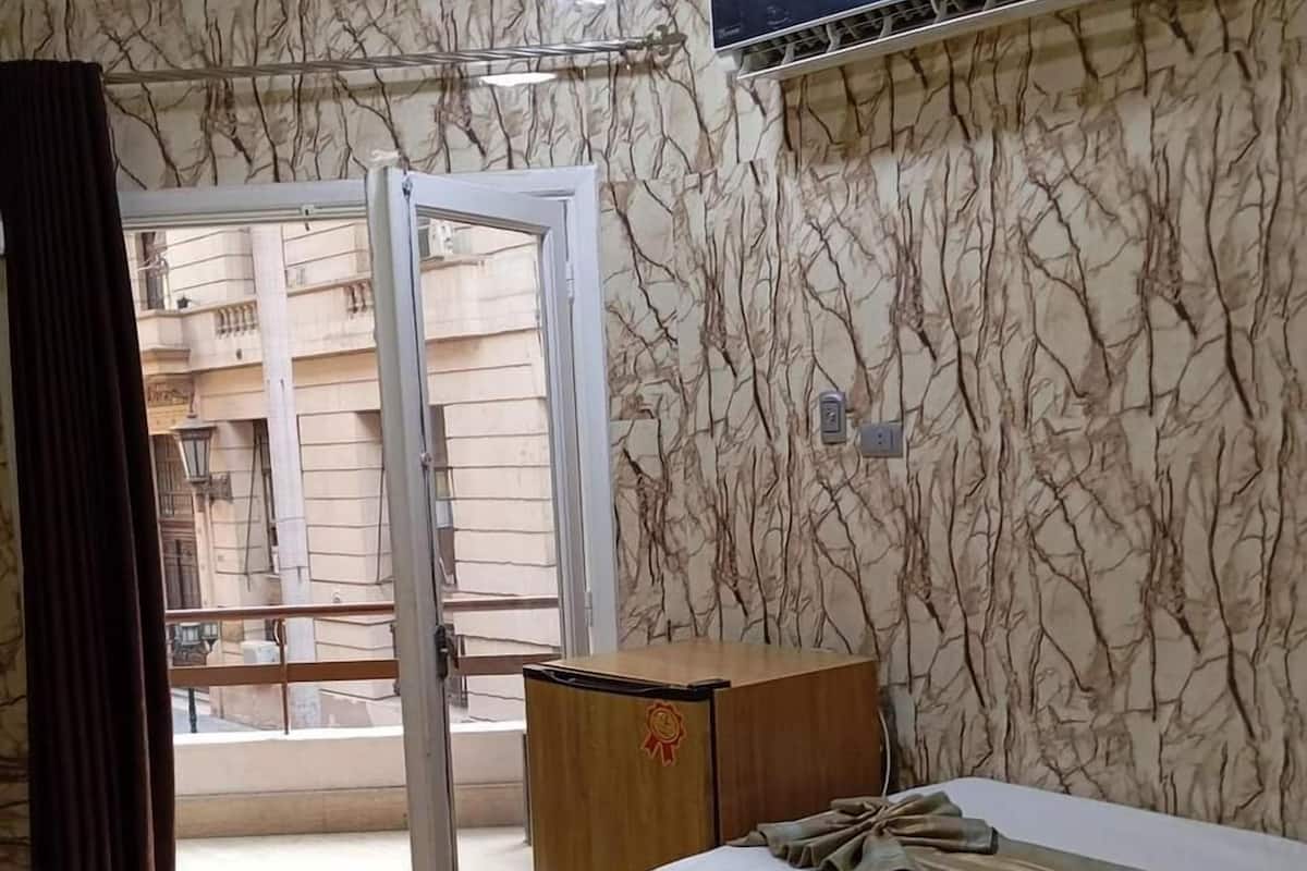 A hotel room with two beds, a wooden wardrobe, a TV, and a door leading to an outdoor area.