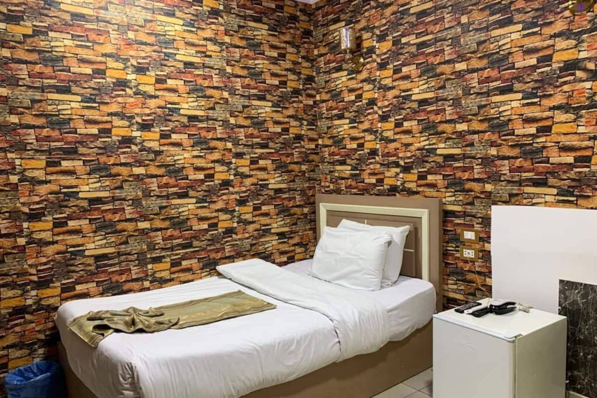 A bedroom with a bed, a bedside table, and a wall covered in a patterned brick design.