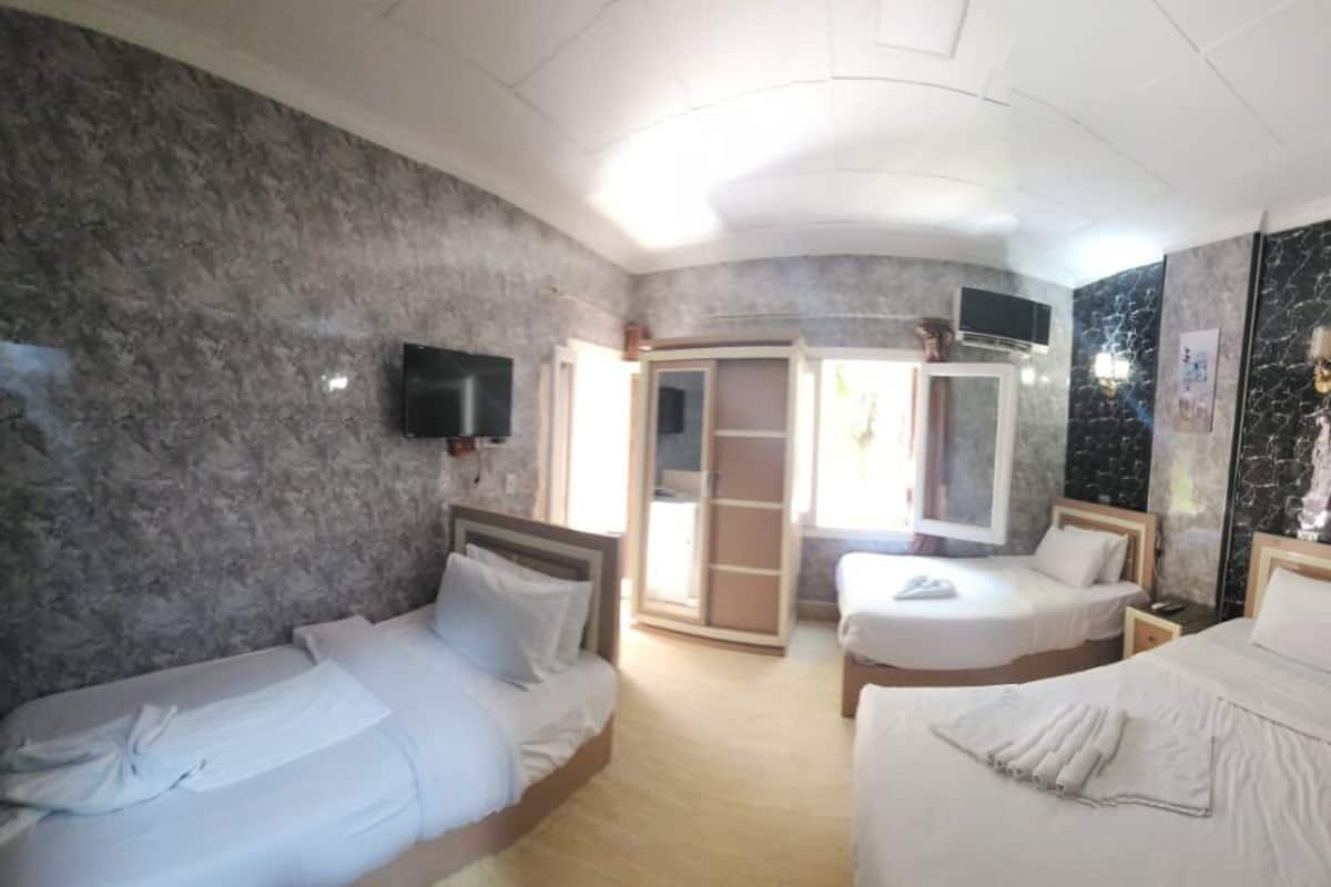 A hotel room with two beds, a TV mounted on the wall, and a sliding door leading to a balcony.