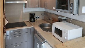 A compact kitchen with a stainless steel range hood, a built-in microwave, a coffee maker, a sink, and a dishwasher. - Lovely 2-room apartment, slopeside, sleeps 6 (Les Orres)