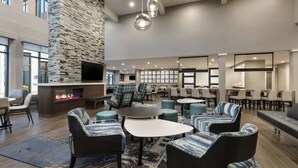 A spacious lobby with a stone fireplace, comfortable seating, and a large TV screen.
