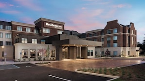 A modern hotel with a prominent "Residence Inn by Marriott" sign, a spacious parking lot, and a well-lit entrance.