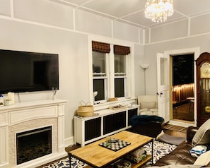 Una sala de estar con chimenea, televisor, mesa de centro y puerta que da al exterior.
