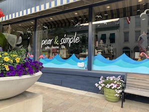 A storefront with a large window display featuring a sign that reads "pear & simple" and mentions "gifts, home, life".