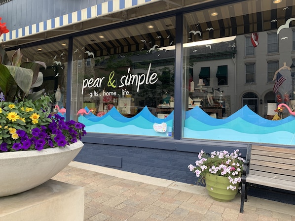 Una tienda con un escaparate grande que muestra un letrero que dice "pear & simple" y menciona "regalos, hogar, vida".
