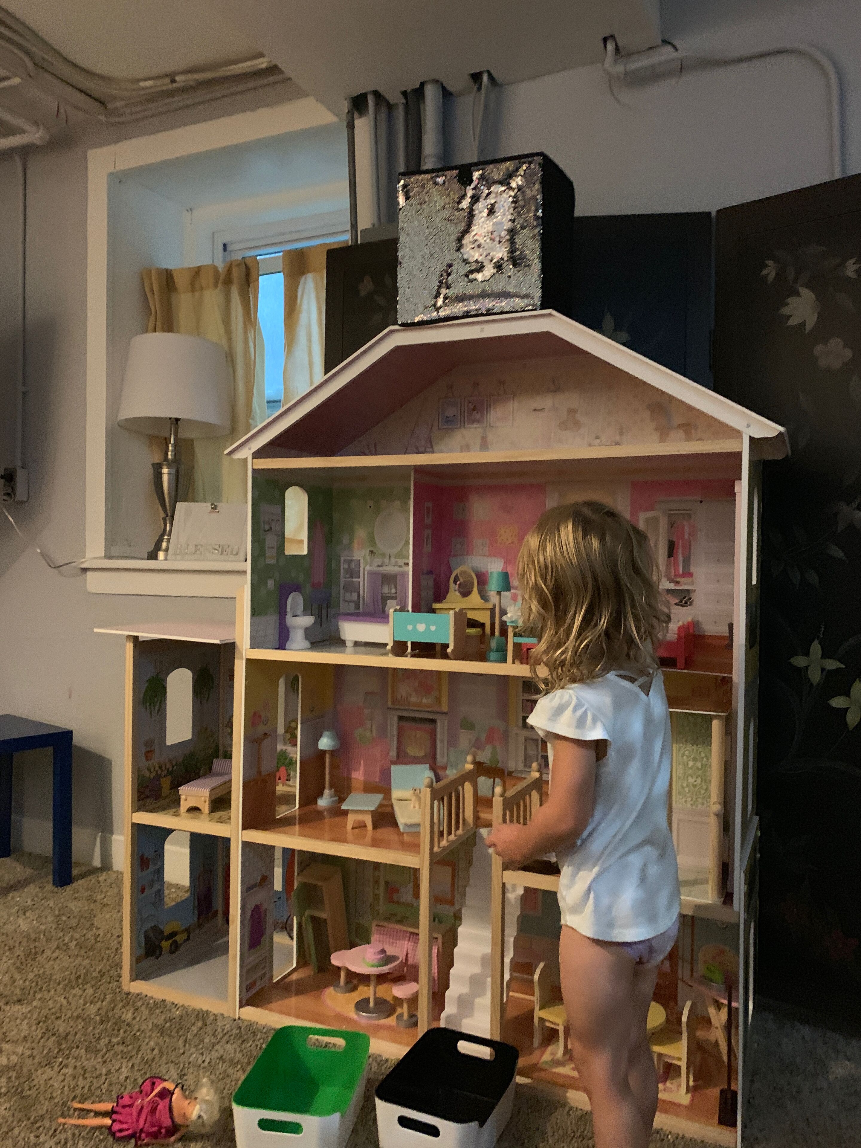 Ein Puppenhaus mit mehreren Zimmern, einem Fenster und einer Lampe.