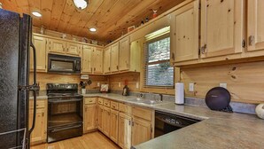 A kitchen with wooden cabinets, a microwave, stove, oven, and a sink.
