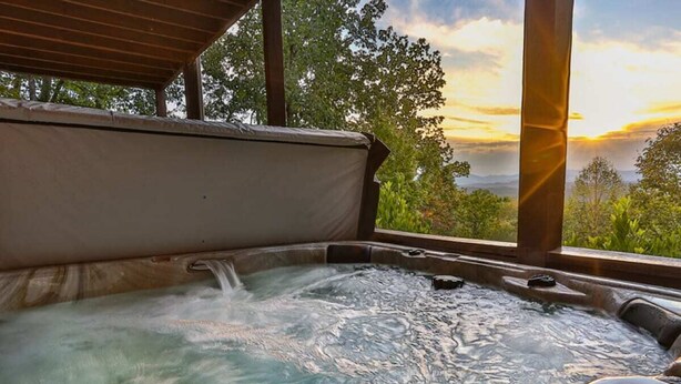 A hot tub with a view of a sunset and greenery.