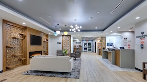 Um lobby de hotel moderno com balcão de recepção, área de estar e lareira.
