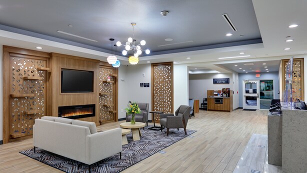Um hall de hotel moderno com lareira, área de estar e um espaço para café.