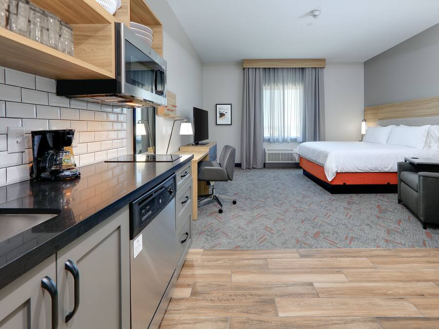 Una habitación de hotel con kitchenette, cama, escritorio y televisor.