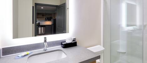 A modern bathroom with a large mirror, a sink, a toilet, and a glass shower enclosure.