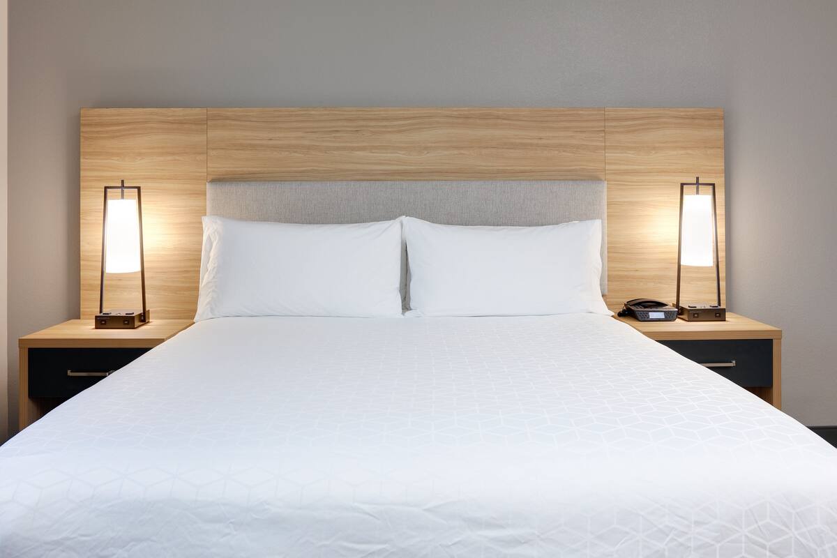A neatly made bed with a wooden headboard, two bedside tables with lamps, and a small radio.