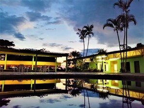 Un hotel con piscina que refleja los edificios y las palmeras.