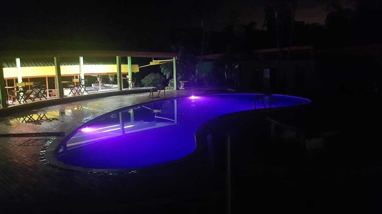 An outdoor swimming pool with a curved edge and a small deck area.