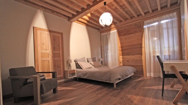A bedroom with a bed, a chair, a desk, and a wardrobe.
