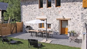 A stone building with a patio, outdoor seating, and a wooden fence.