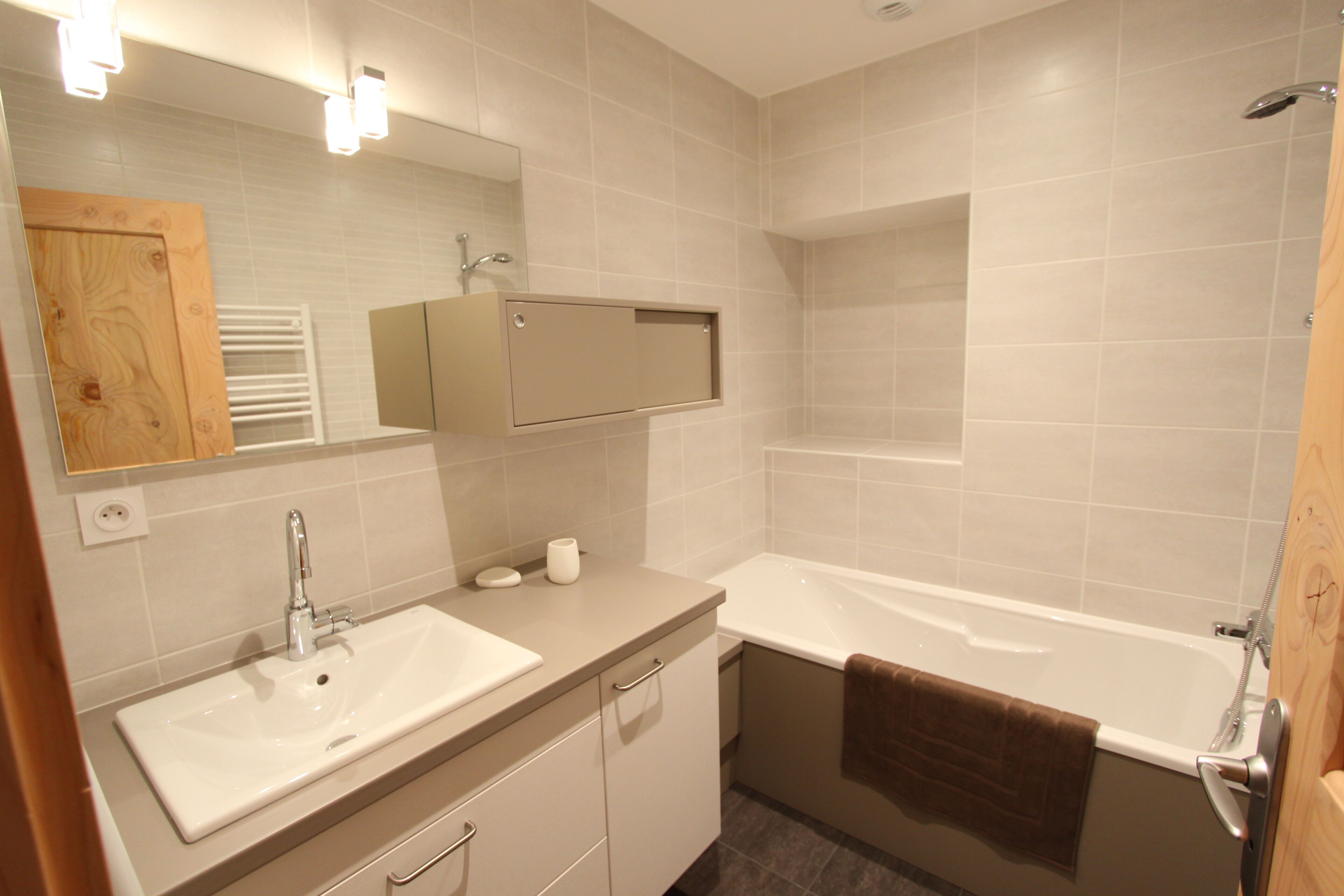 Une salle de bain moderne avec un lavabo, un miroir, un meuble et une baignoire.