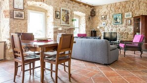 A rustic stone-walled room with a dining table, chairs, a sofa, and a television. - near Dubrovnik City Walls (Dubrovnik)