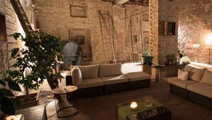 Um interior rústico com paredes de tijolo aparente, vigas de madeira e uma área de estar acolhedora com sofás e uma mesa de centro.