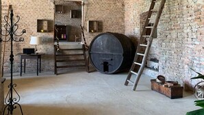 Quarto rústico com paredes de tijolos aparentes, teto de madeira e um grande barril.