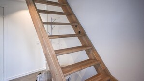 A wooden ladder leaning against a white wall in a room with a door and a wicker basket on the floor. - Lovely home in Unnaryd with WiFi (Unnaryd)