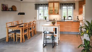 A modern kitchen with wooden cabinets, a dining area with a table and chairs, and a small island with a sink. - Lovely home in Unnaryd with WiFi (Unnaryd)
