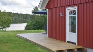 A red building with a wooden deck leading to a white door, overlooking a lake. - Lovely home in Unnaryd with WiFi (Unnaryd)
