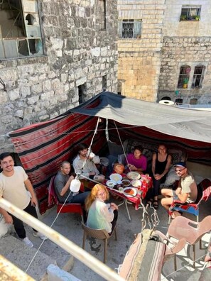 A group of people dining outdoors with a tent and tables.