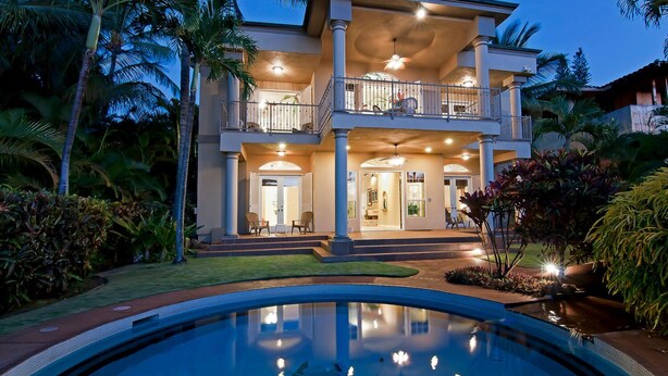 A two-story house with a swimming pool, surrounded by tropical vegetation.