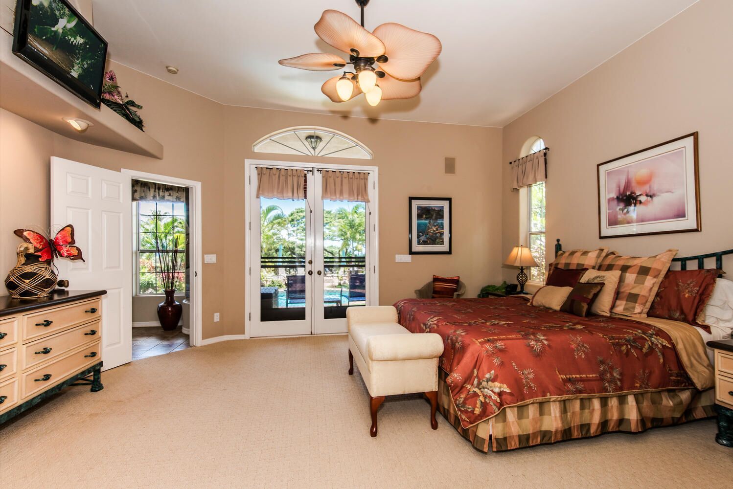 A bedroom with a bed, a desk, a chair, a dresser, a ceiling fan, and a window with curtains.