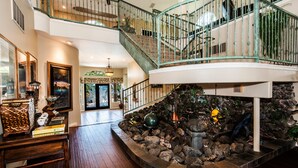 A spacious foyer with a curved staircase, a decorative fountain, and a wooden reception desk.