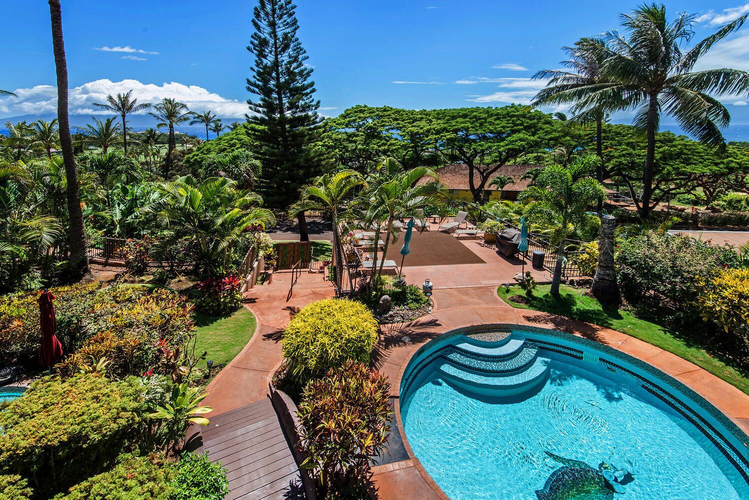 Un resort con piscina rodeada de vegetación tropical y vista al océano.