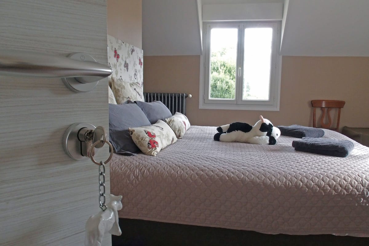 Ein Schlafzimmer mit einem Bett, Kissen, einem Schlüsselanhänger, einem Heizkörper und einem Fenster.