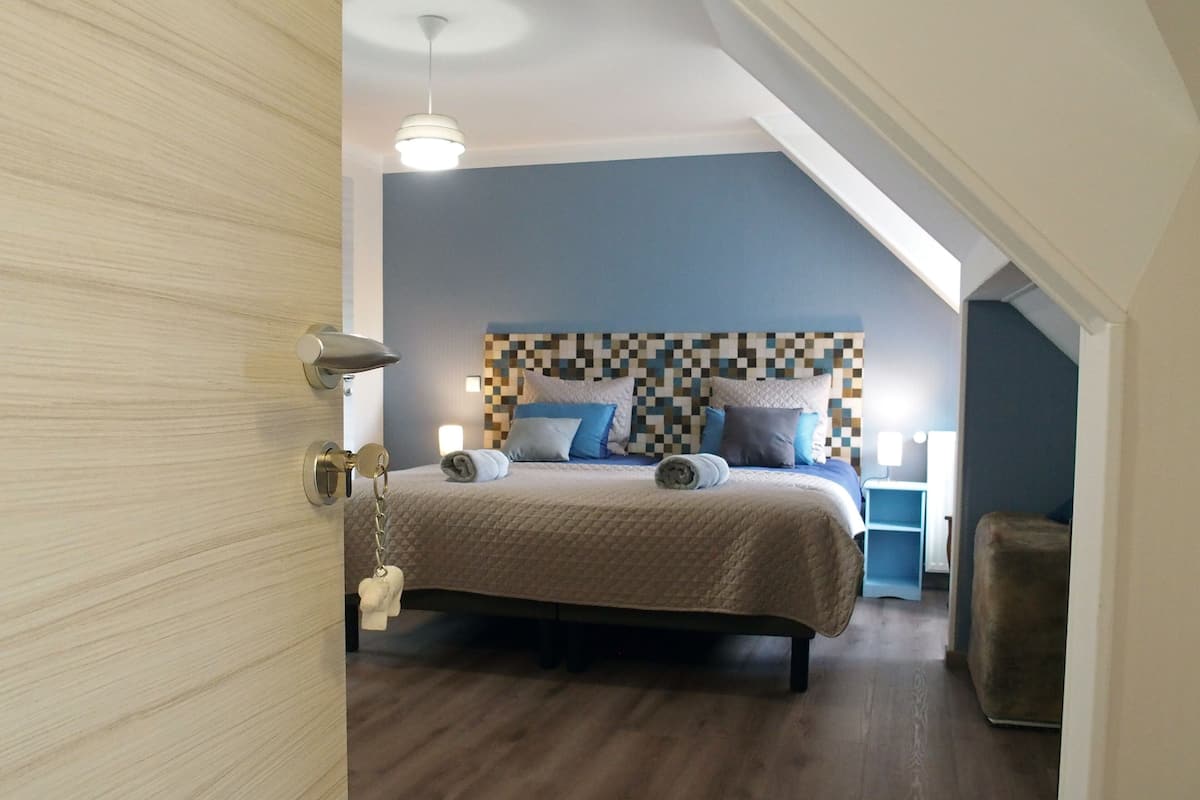Ein Schlafzimmer mit Bett, Nachttisch, Lampe und Deckenleuchte.