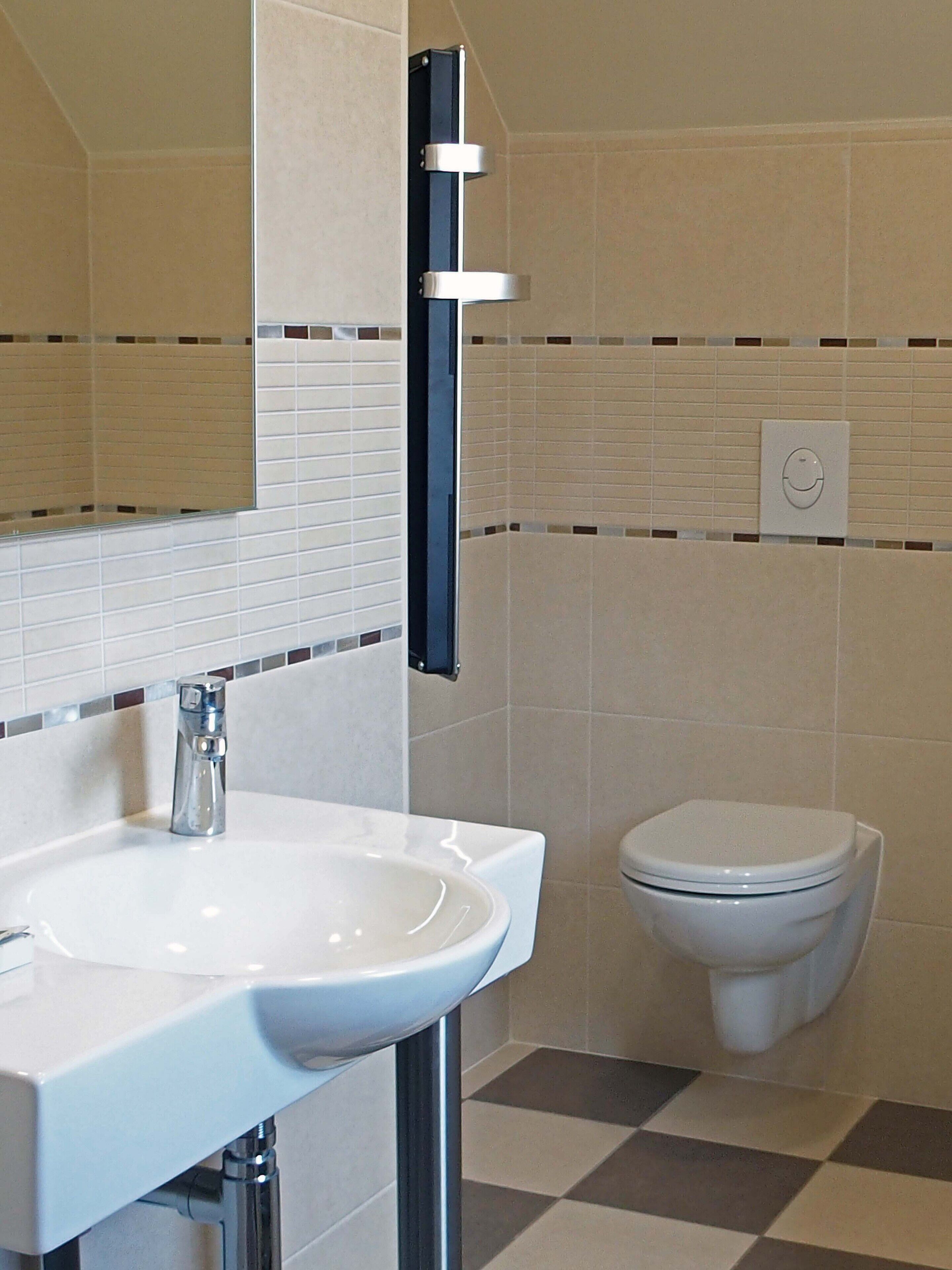 Ein Badezimmer mit einem weißen Waschbecken, einer Toilette und einem Spiegel.