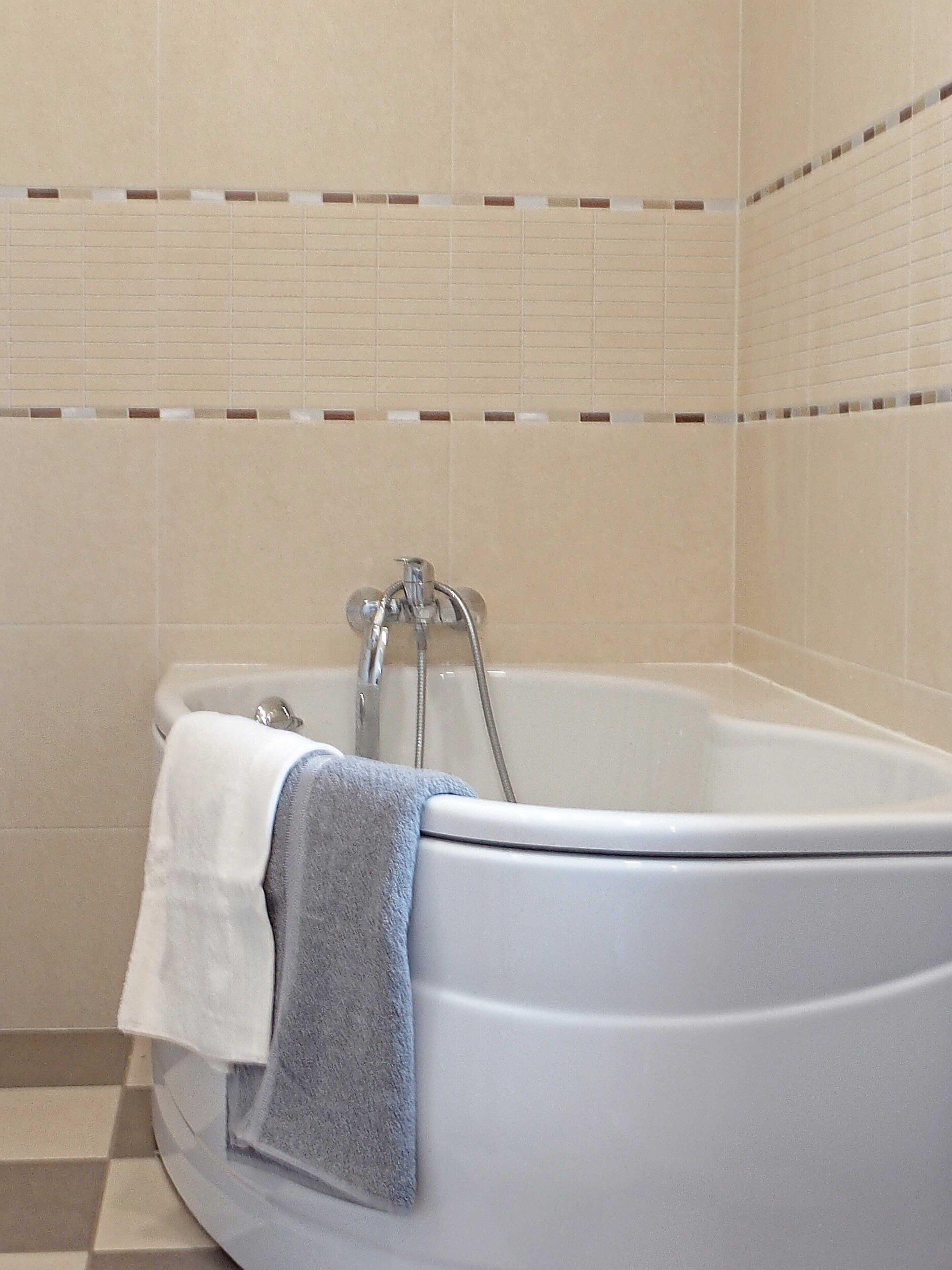 Una bañera con una toalla blanca y una azul.