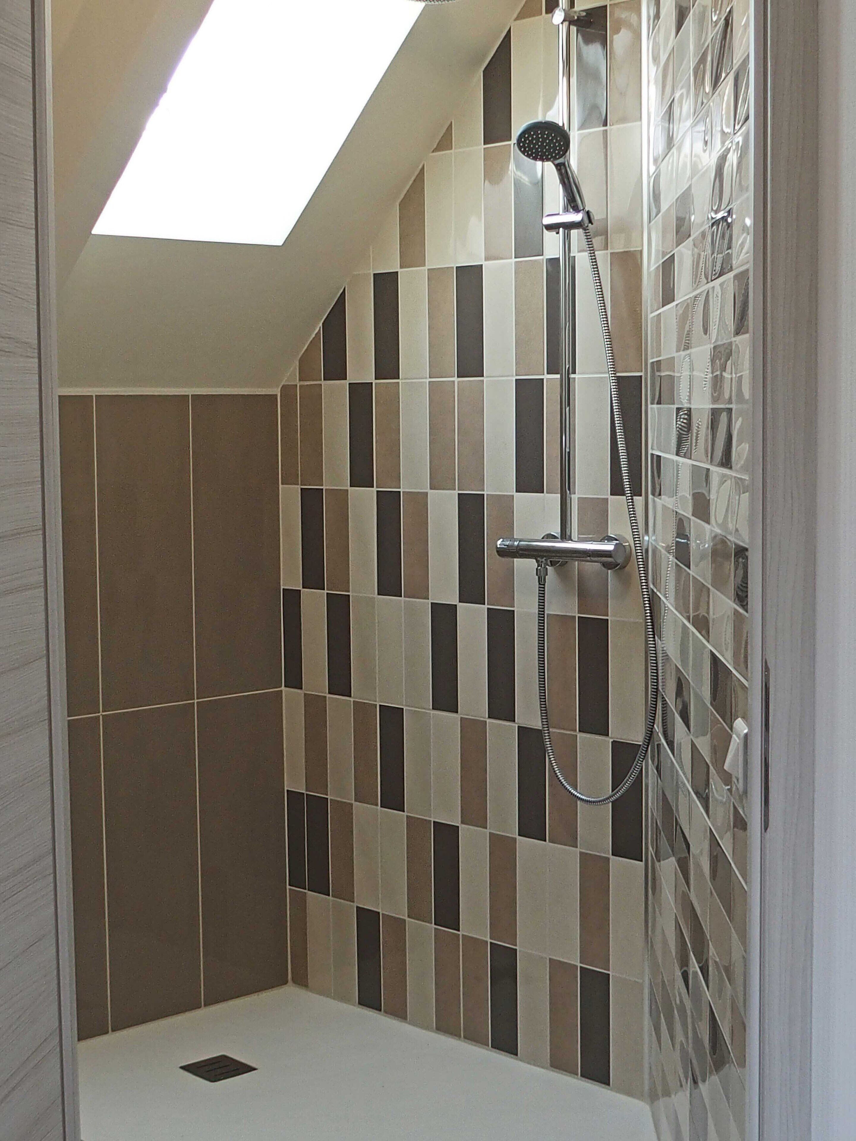 Una ducha con techo inclinado y paredes de azulejos.