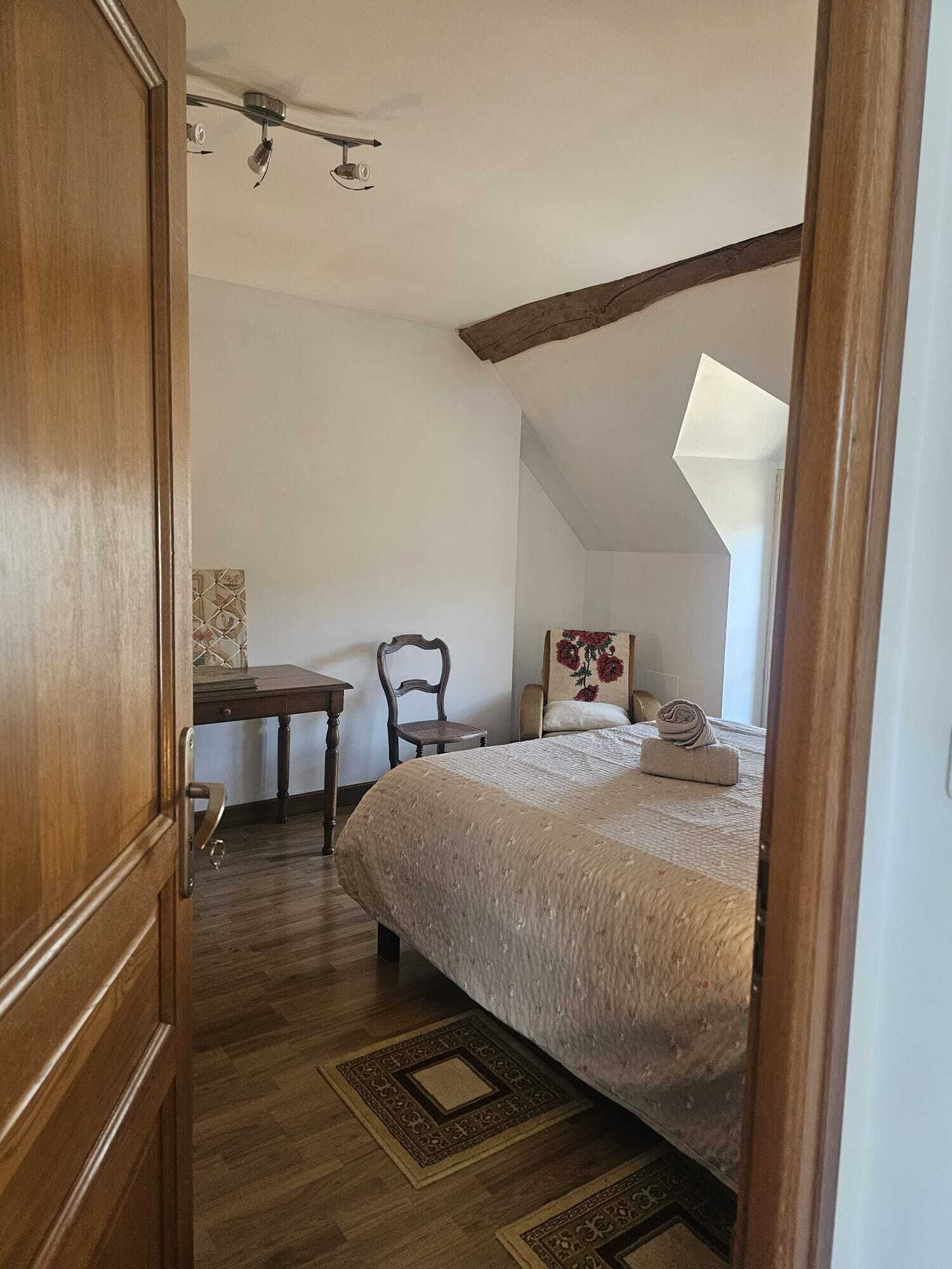 Un dormitorio con cama, una silla, un escritorio y un ventilador de techo.