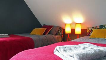Une chambre à coucher avec deux lits, chacun recouvert d’une couvre-lit rouge et grise, et deux lampes de chevet.