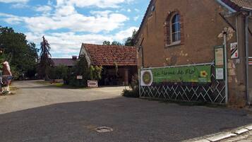 A rustic building with a tiled roof, a signboard, and a fenced area.