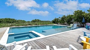 Ein rechteckiger Pool mit Holzterrasse und Liegestühlen.