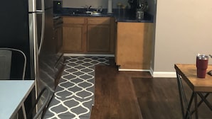 Una cocina compacta con armarios de madera, un refrigerador de acero inoxidable, un microondas y una cafetera.
